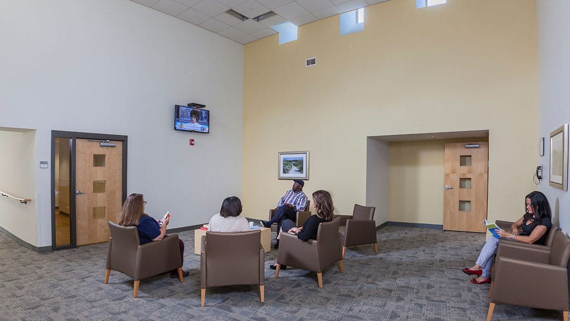 Group of people seated in chairs watching a wall-mounted TV