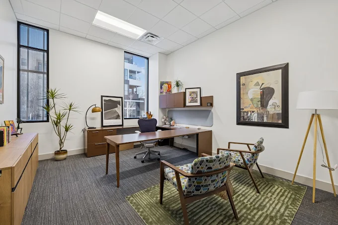 A cozy therapy office with two modern armchairs and a desk.