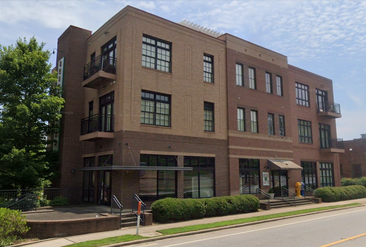 A three-story brick building with large windows and balconies