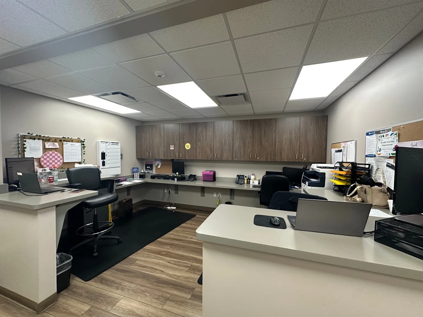 Staff workstation with computers, counters, cabinets, and office equipment