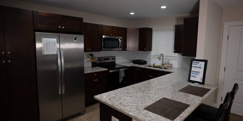  A modern kitchen with dark wood cabinets, stainless steel appliances, and a sleek granite countertop, creating a stylish and functional space.