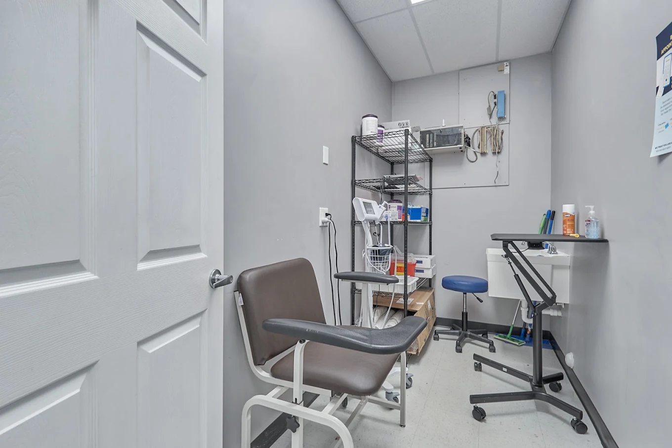 Clinical exam room with chair, sink, and medical equipment