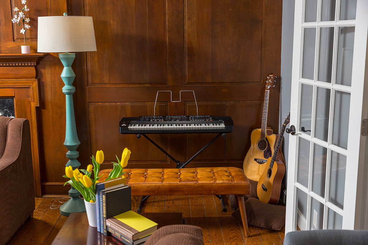 Keyboard and guitars in cozy wood-paneled room