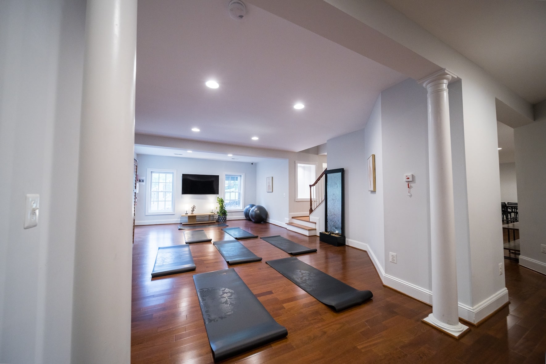 A bright fitness space with yoga mats and a large TV in the background