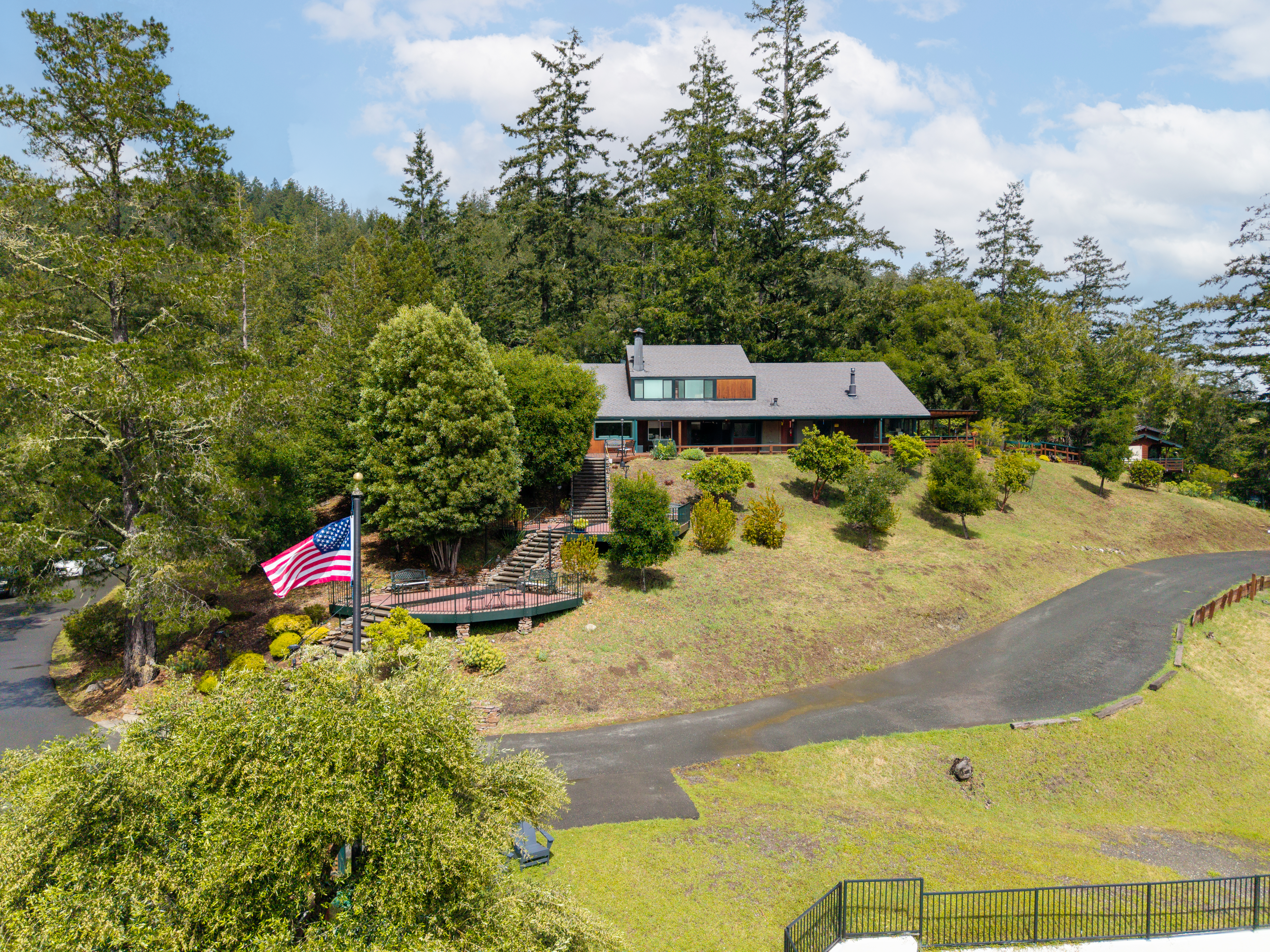 Aerial view of Serenity Knolls Treatment Center showing the swimming pool, residential buildings, expansive grounds, and surrounding forest in Forest Knolls, California.