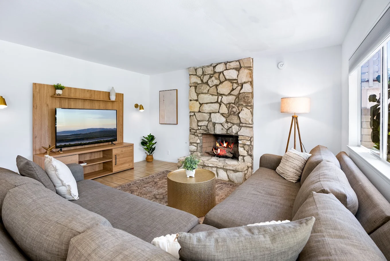 Lounge with sectional sofas, stone fireplace, and TV