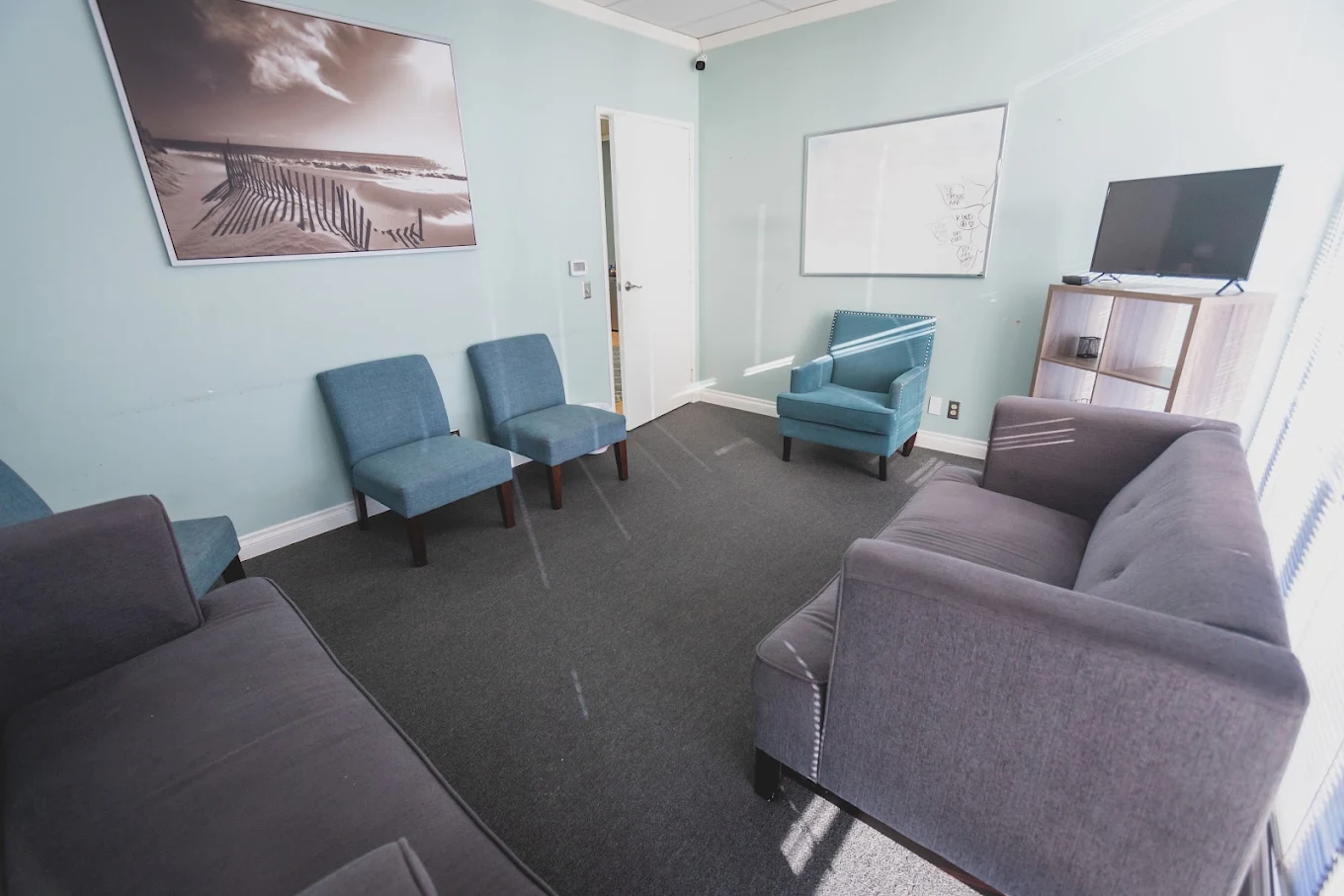 Counseling room with sofas, armchairs, and wall-mounted TV