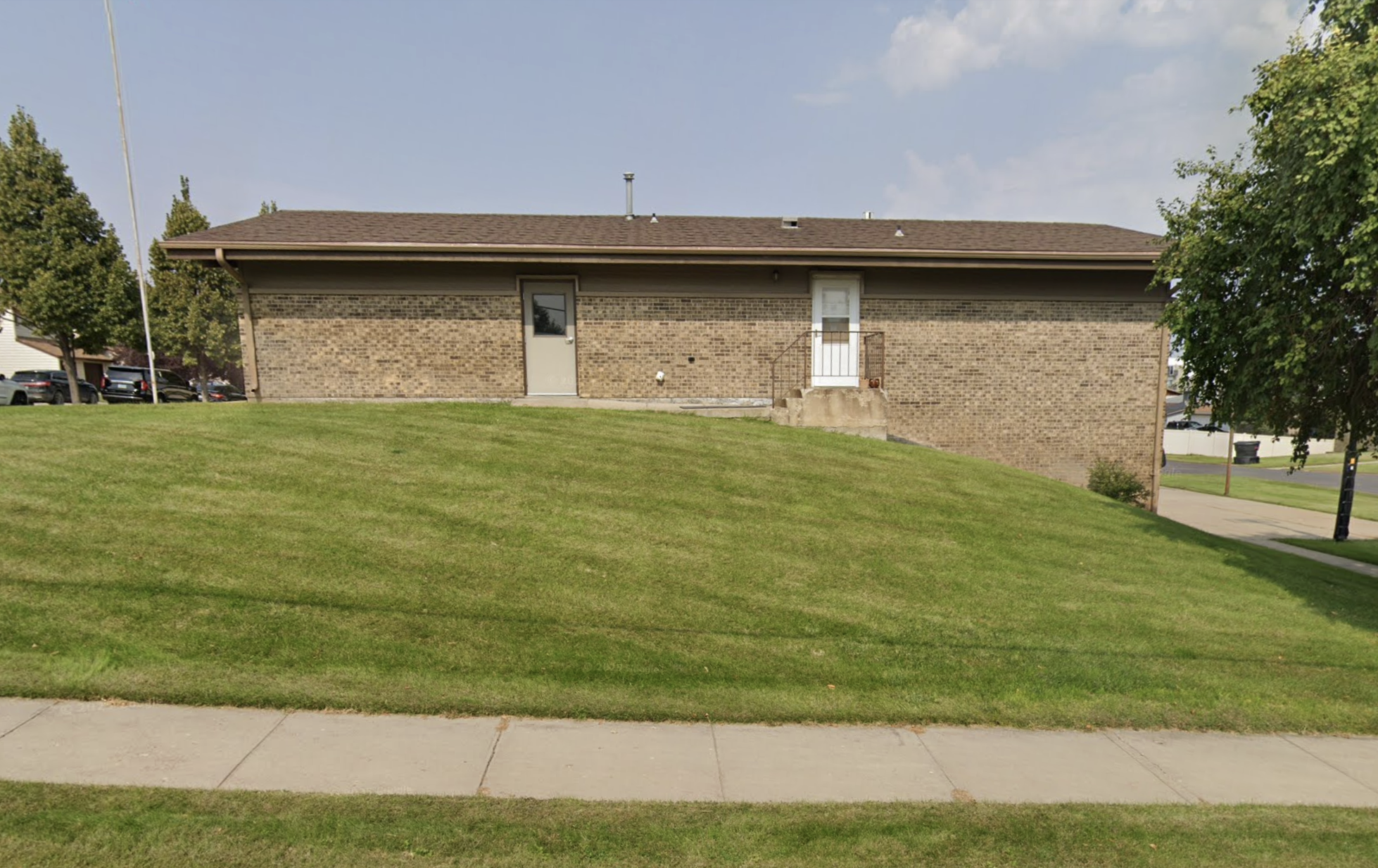 Single-story brick rehab building on grassy slope