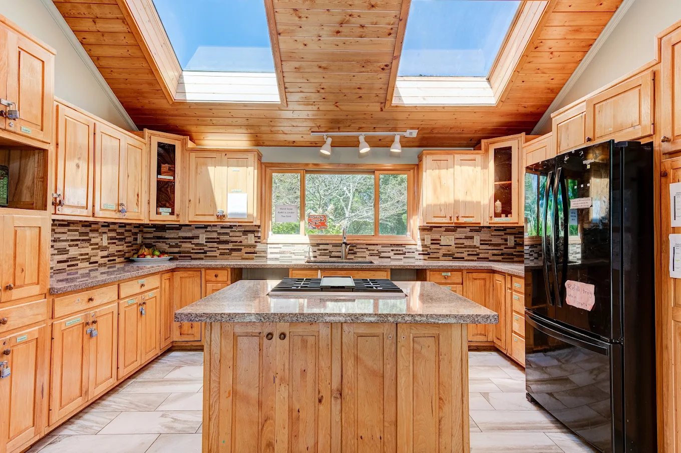 Sunlit kitchen with wood cabinets, island and skylights