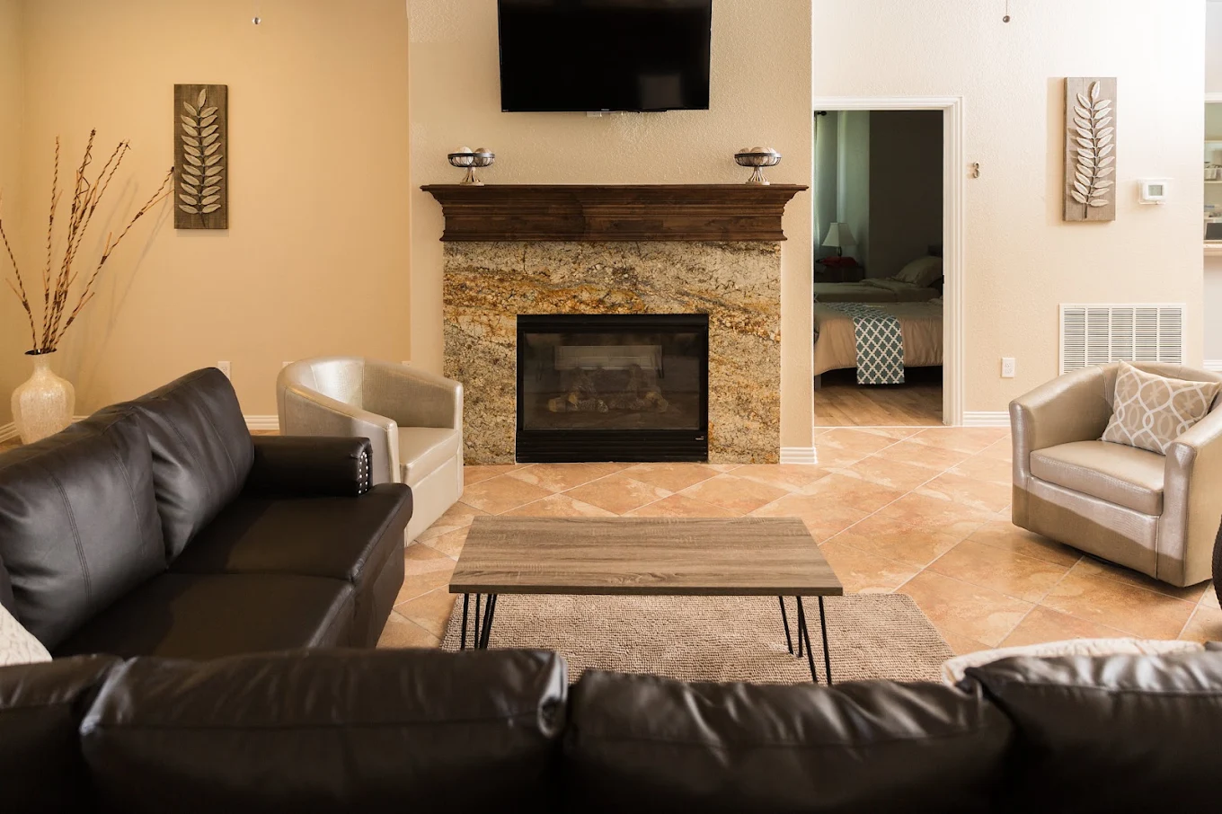 Comfortable lounge with leather sofas, armchairs, a stone fireplace, wall-mounted television, and neutral decor