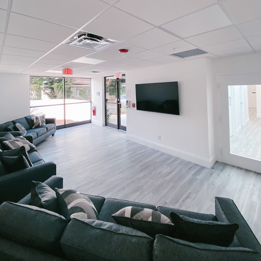 Lounge area with  sofas, a  TV, and modern decor, and exit in view.