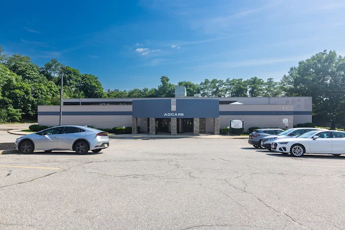 Wide view of AdCare facility with parking lot and cars
