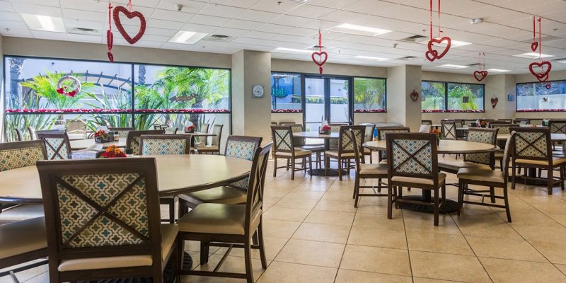  Bright dining area adorned with heart decorations, featuring round tables and comfortable chairs, offering a warm and inviting atmosphere.