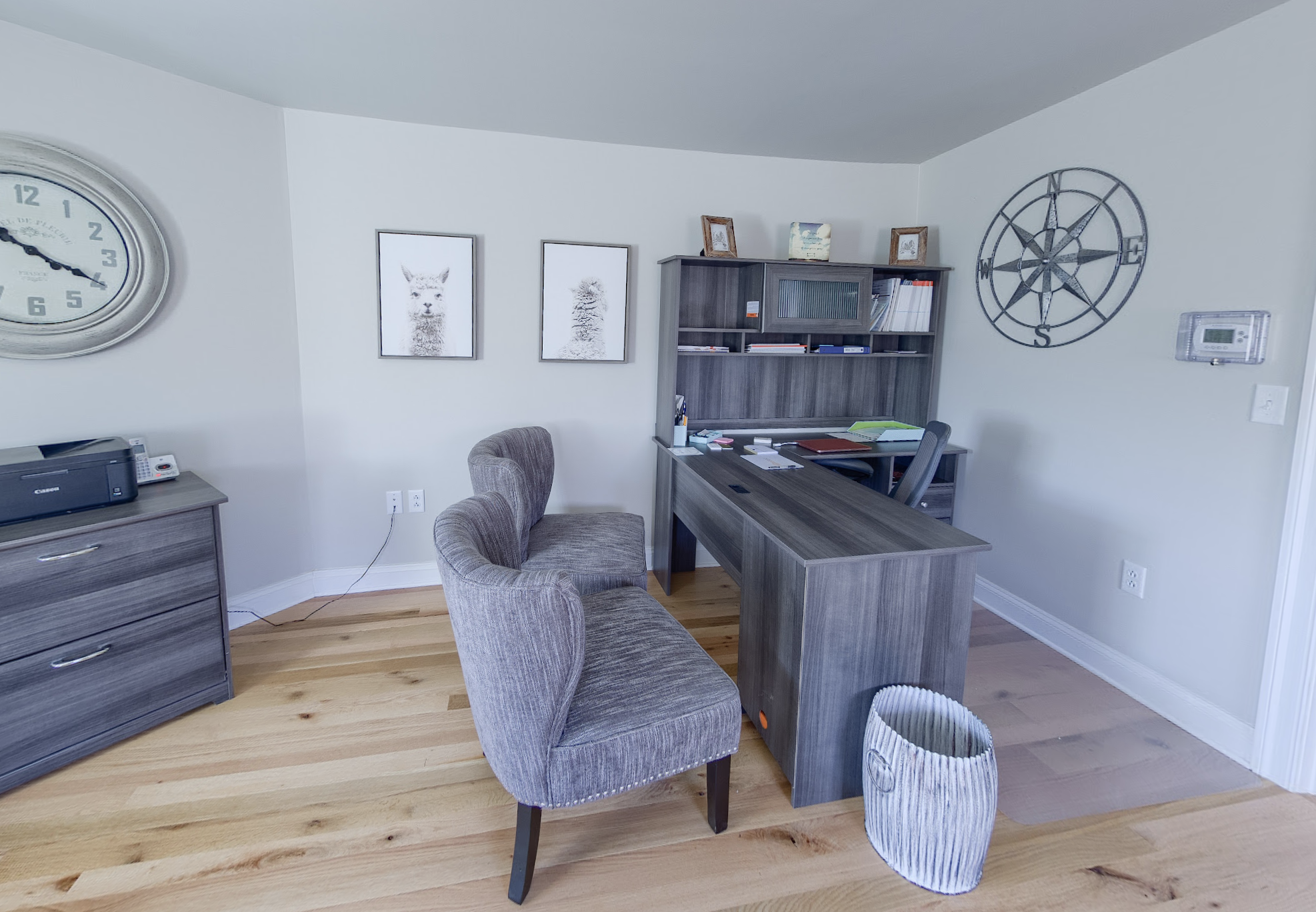 Office with wooden desk, upholstered chairs, and bookshelf