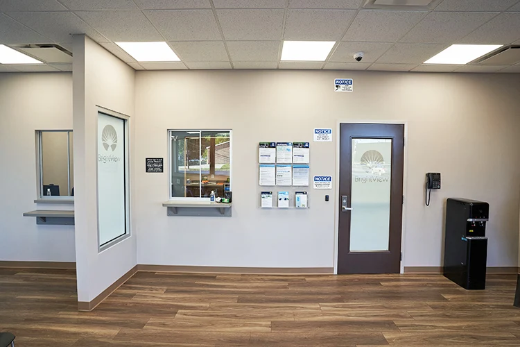 BrightView Health Marion check-in area with service windows, frosted BrightView doors, informational notices, wood-look flooring, and water dispenser
