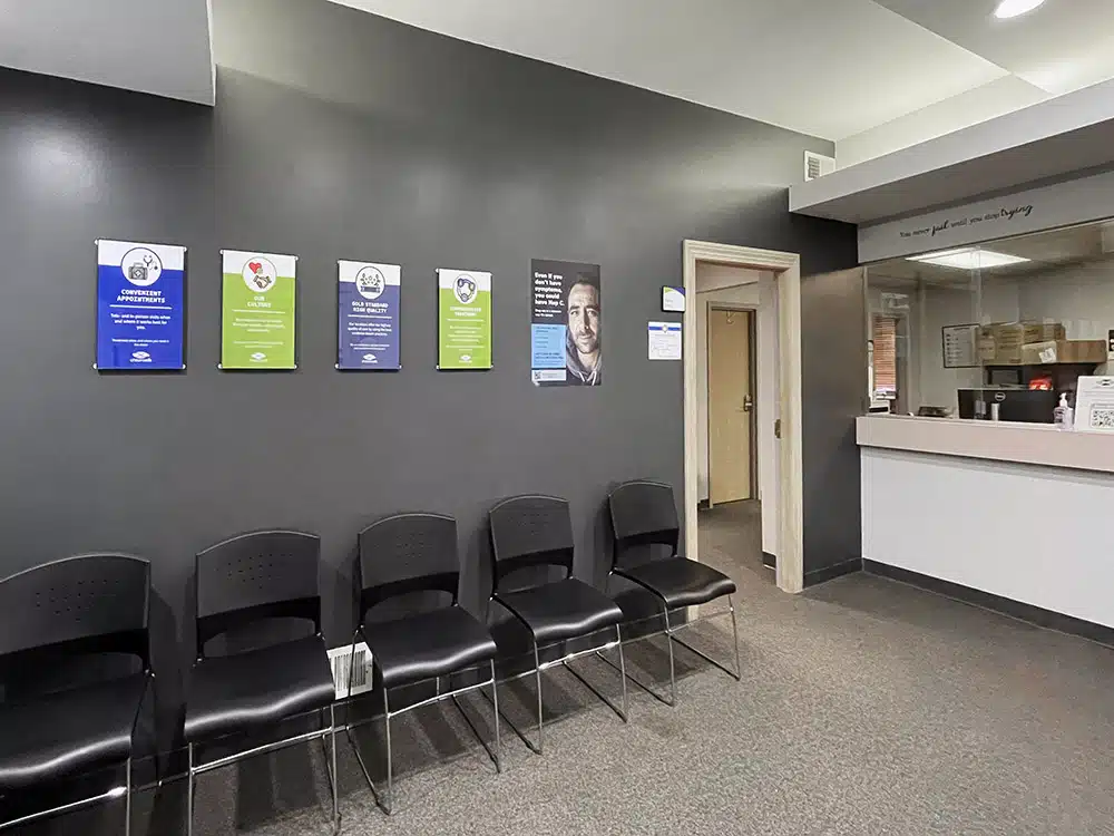 Row of black chairs beneath colorful informational posters in a clinic waiting room