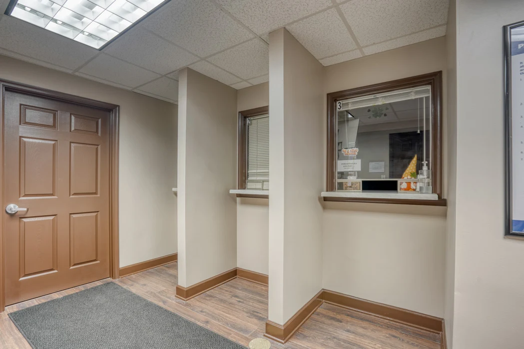 BrightView Health opioid treatment program dispensing area with numbered service windows, privacy partitions, and wood-look flooring