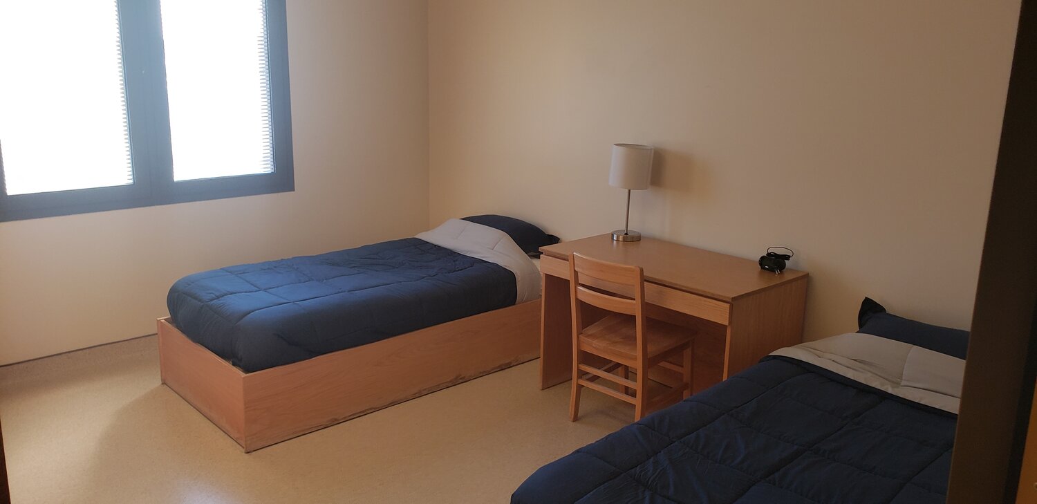 Two twin beds with wood furniture and a desk between them