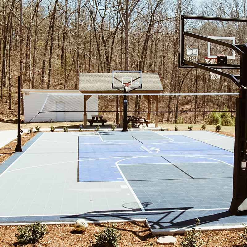 Outdoor basketball court with hoop and wooded surroundings