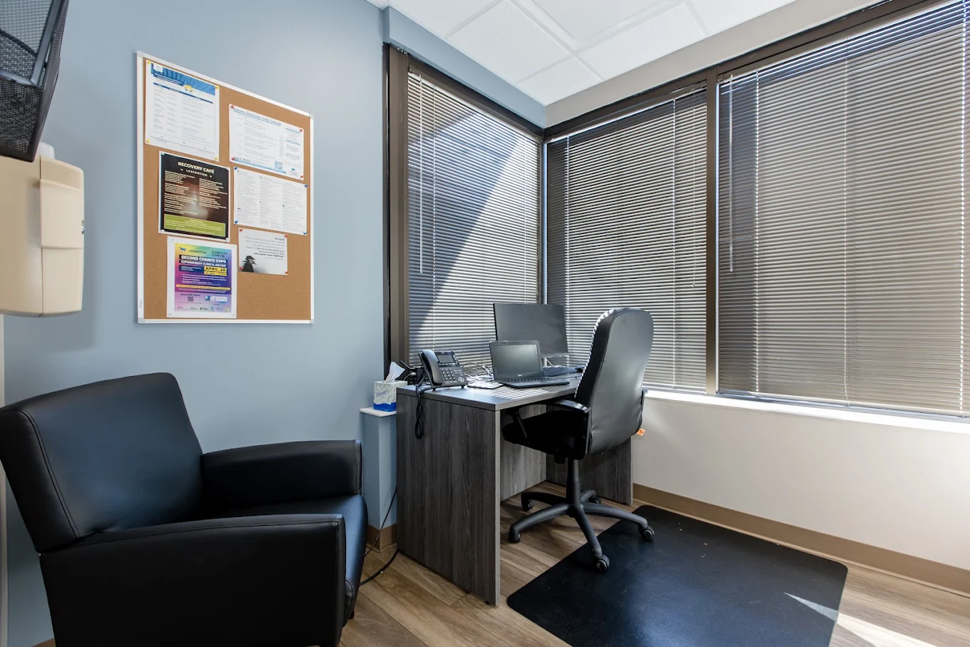 Counseling room with desk, computer, chair, and large windows