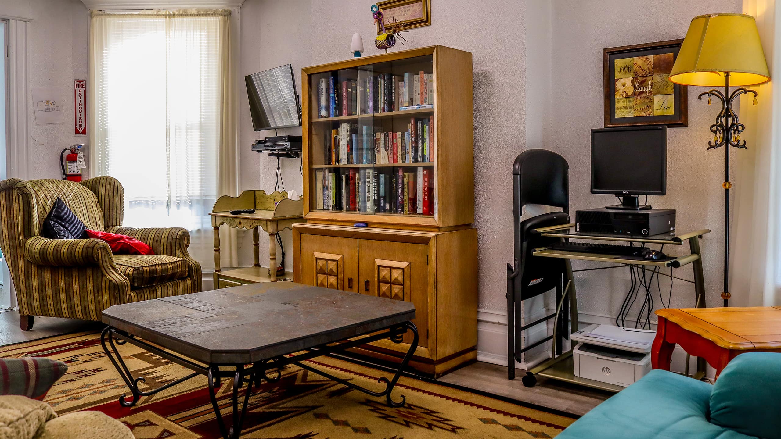 Cozy lounge with striped chair, bookshelf, and computer desk