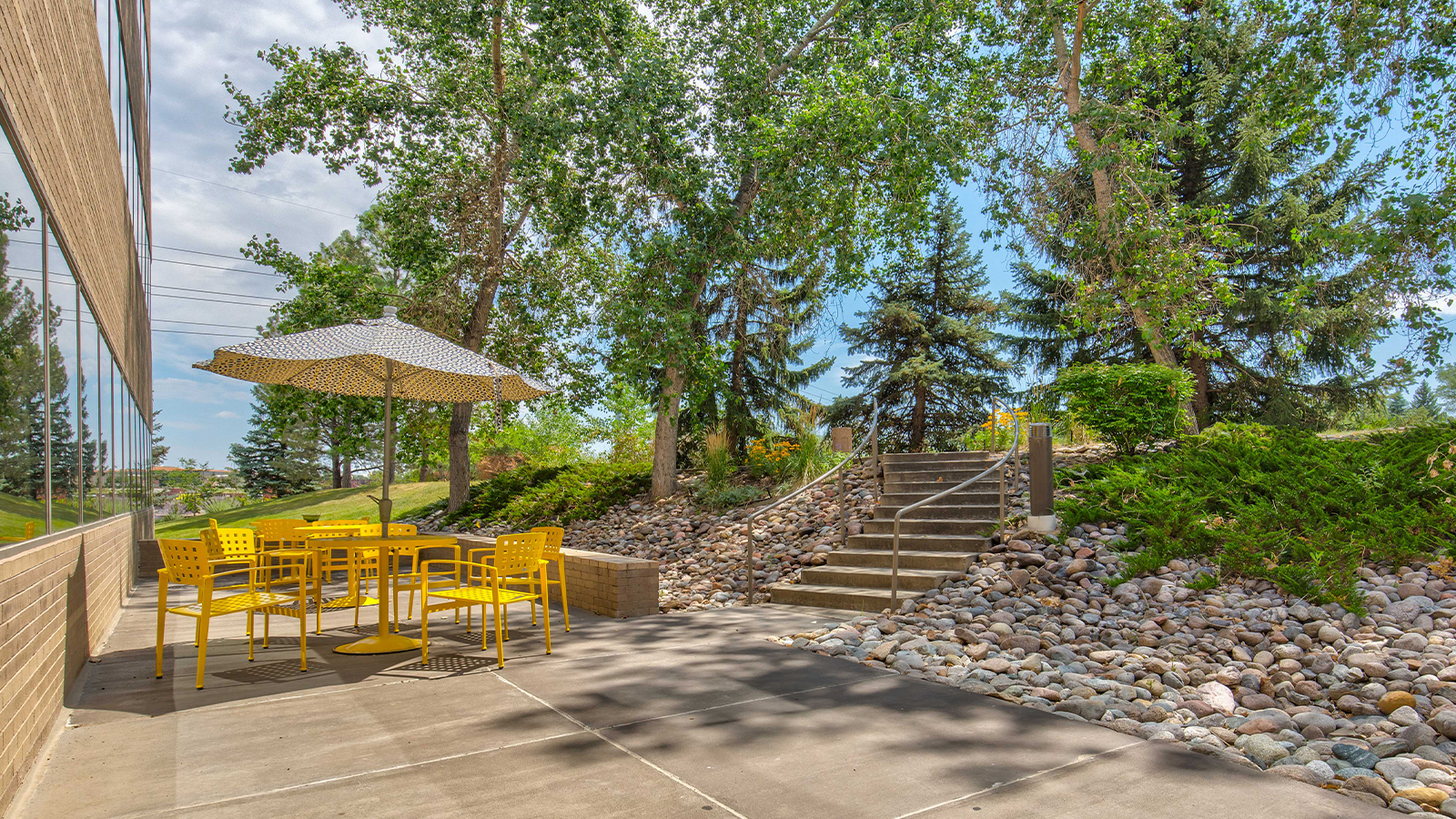 An outdoor seating area with yellow chairs and a patio umbrella.