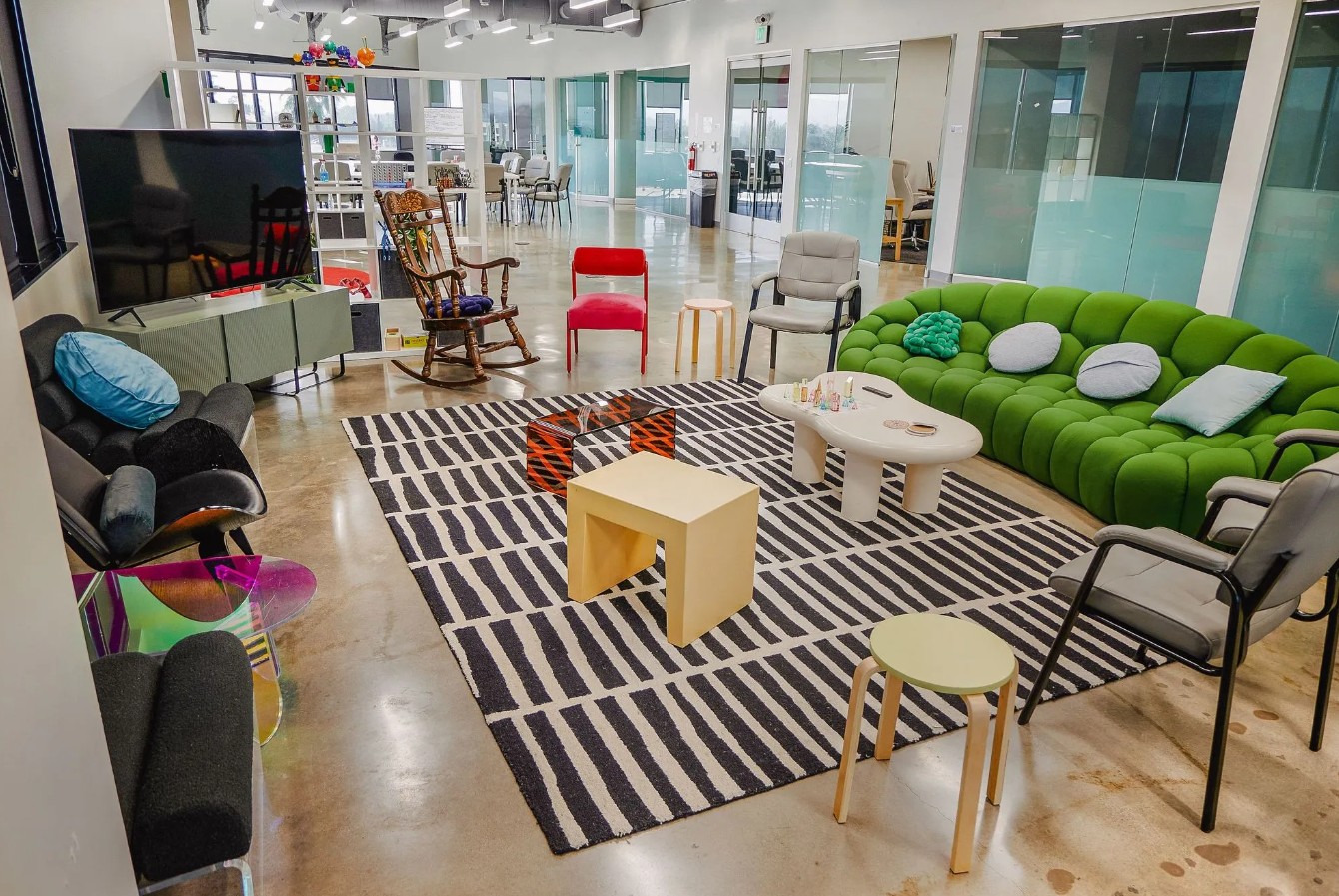 Modern community lounge with colorful seating, television, and open gathering space