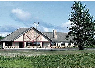 A rehab facility with a large sloped roof and a surrounding natural landscape