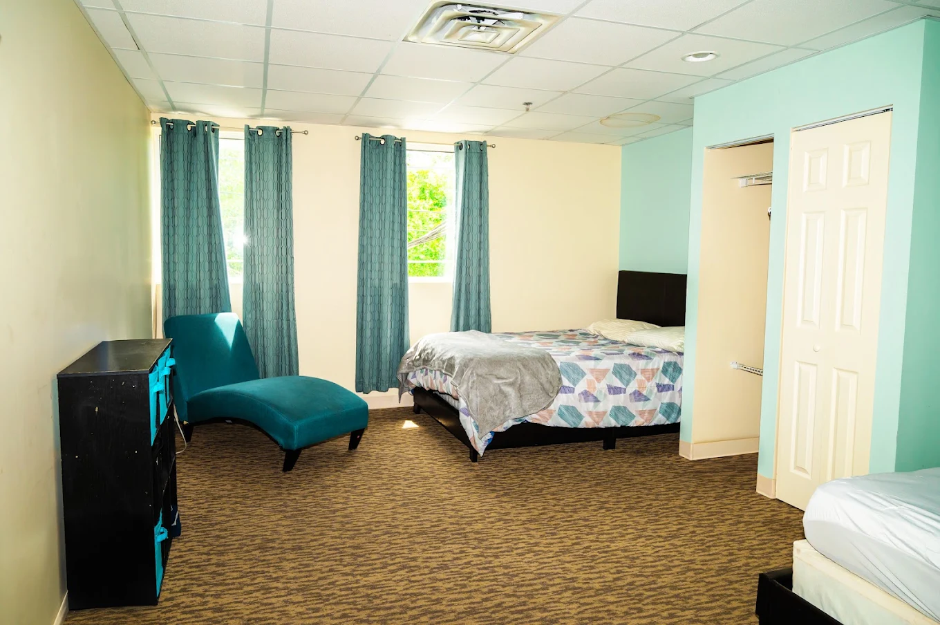 Shared bedroom with beds, lounge chair, and large windows