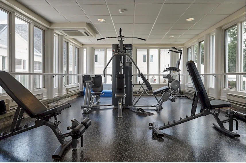 Fitness center with strength training equipment and windows.