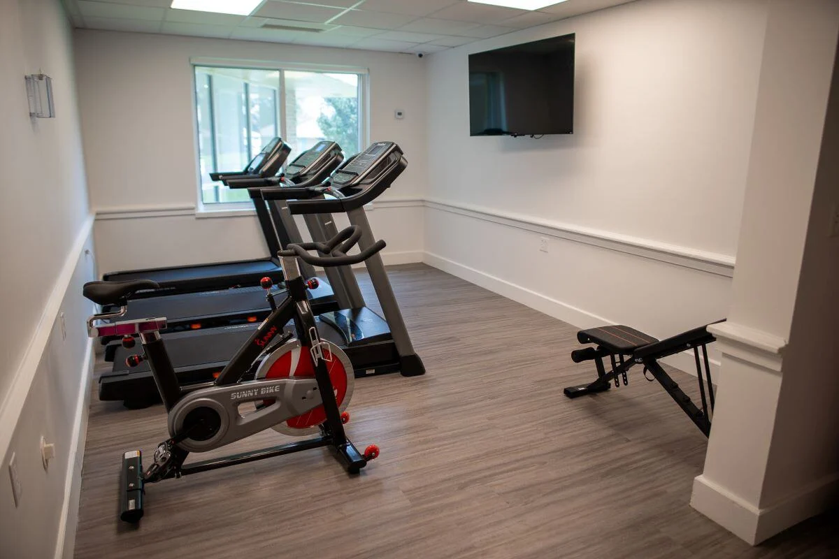 Gym with treadmills, exercise bike, bench, and wall-mounted TV
