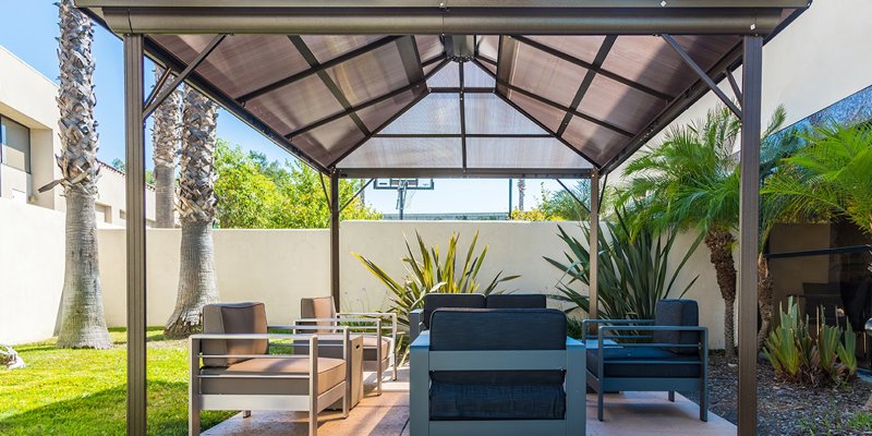 Outdoor seating area under a stylish gazebo, surrounded by lush greenery, offering a relaxing space for conversation and leisure.