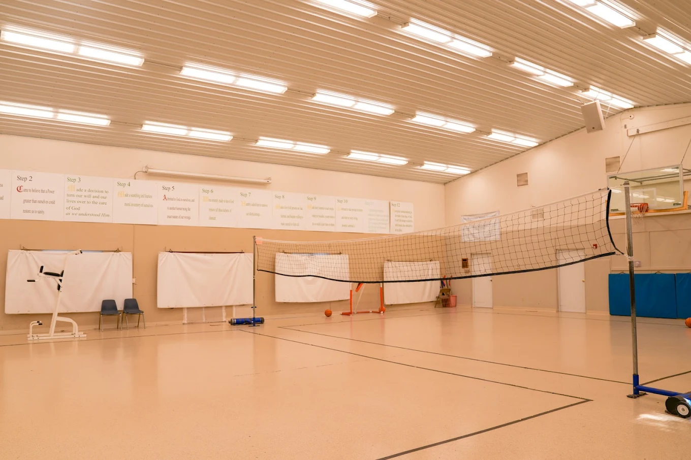 Indoor gym with volleyball net and basketball equipment