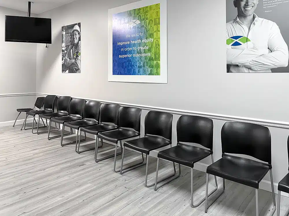 Waiting room with row of black chairs and wall posters