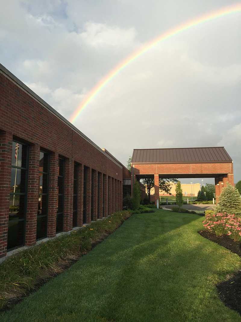 Rainbow arching over brick rehab facility with lawn