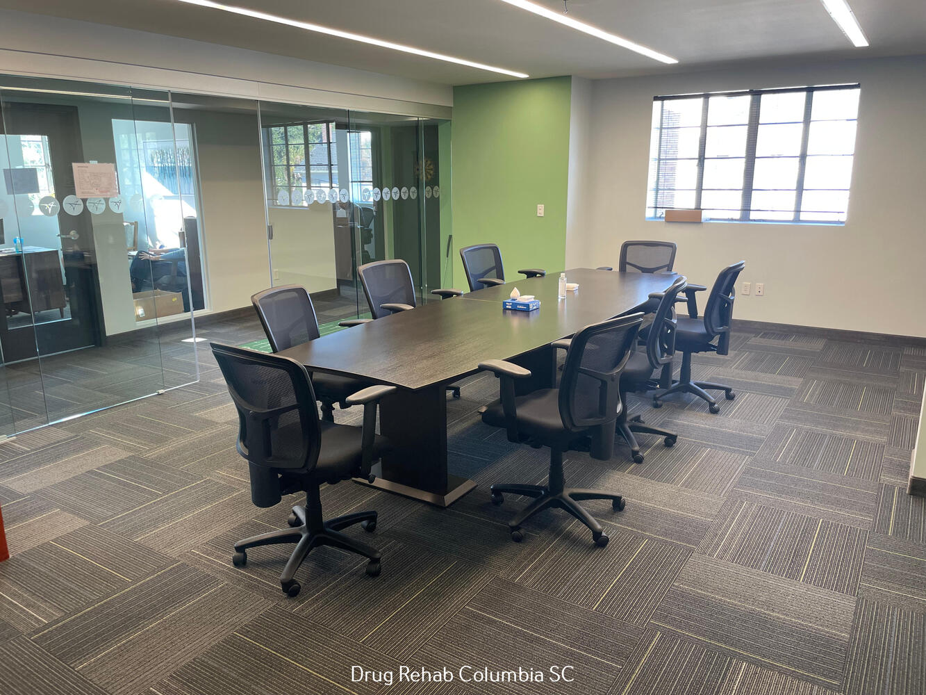 A spacious meeting room with a long table and office chairs