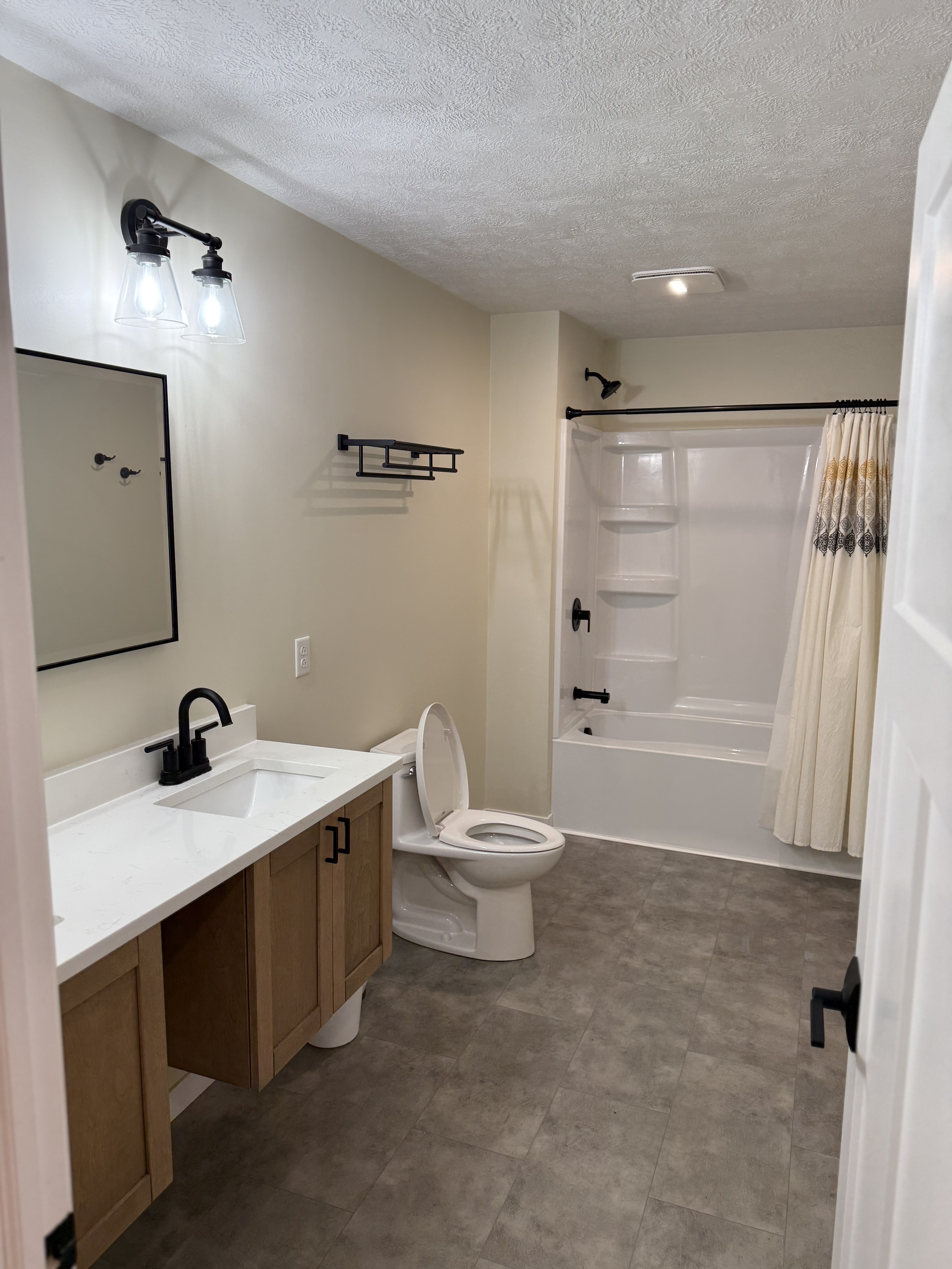 Modern bathroom with white tub, black fixtures, and sink vanity.