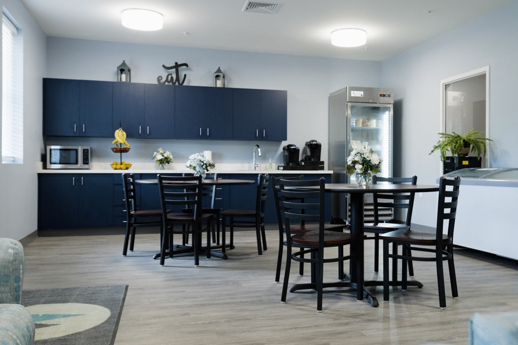 Tables and chairs beside kitchen with blue cabinets