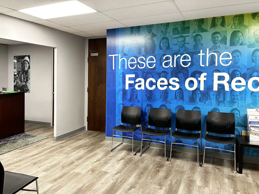 Waiting room chairs beside large Faces of Recovery mural