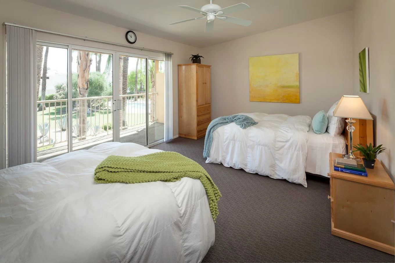 Two beds in a bright room with poolside balcony view