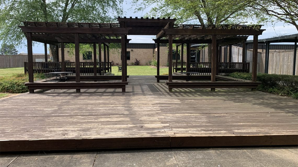 Shaded outdoor pavilion with wooden deck and seating areas