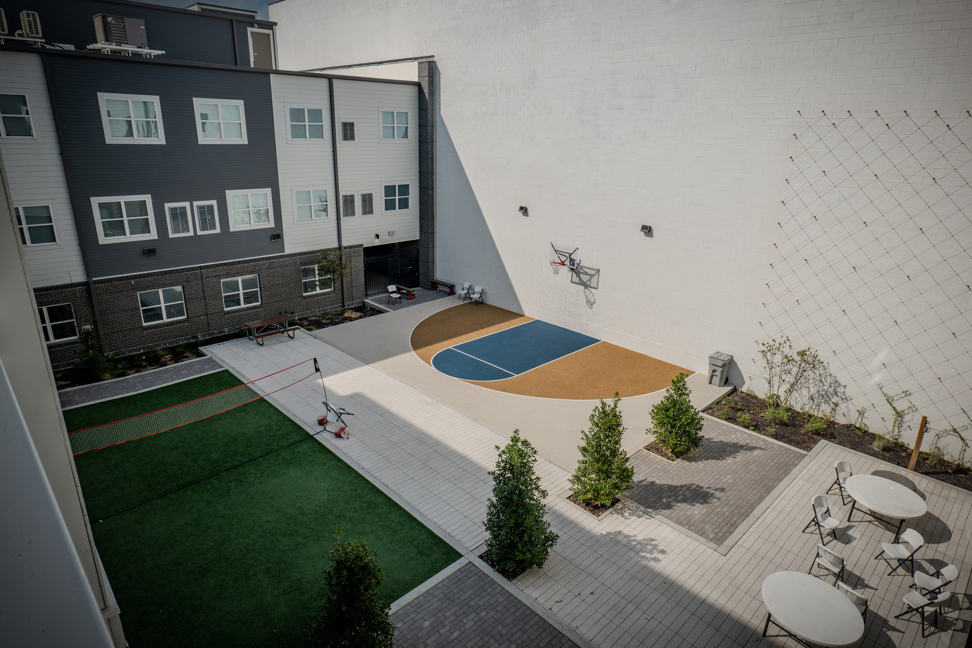 Open courtyard with basketball half-court, volleyball, and seating