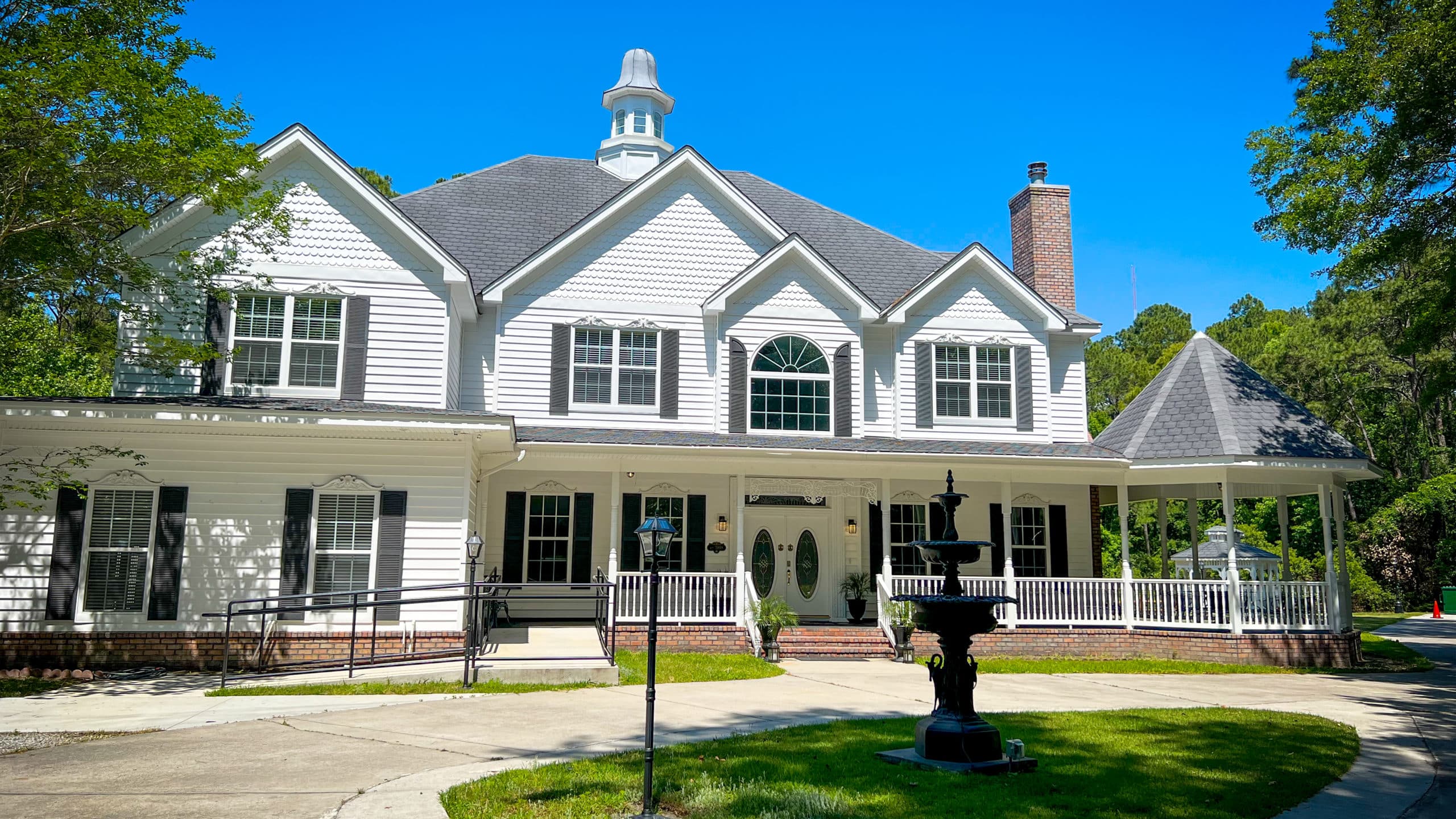 White colonial-style building with wraparound porch