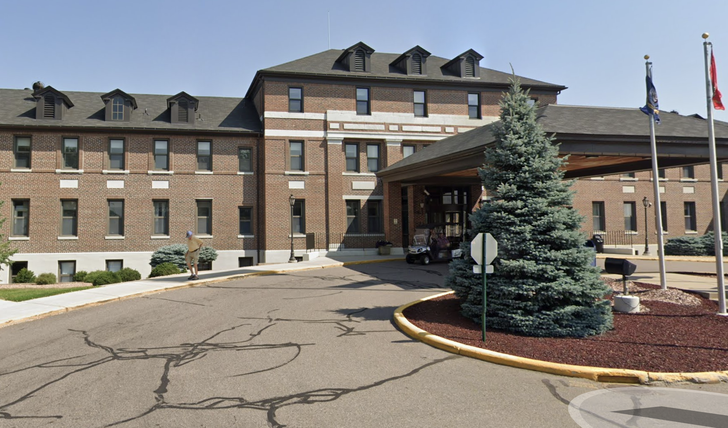 Brick building exterior with driveway and landscaped entrance