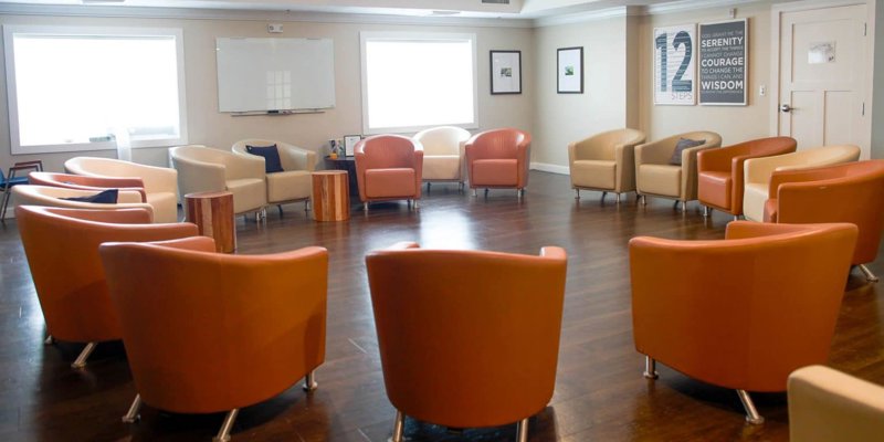 A bright and welcoming group therapy room with a circular arrangement of comfortable chairs, fostering a supportive and collaborative environment.