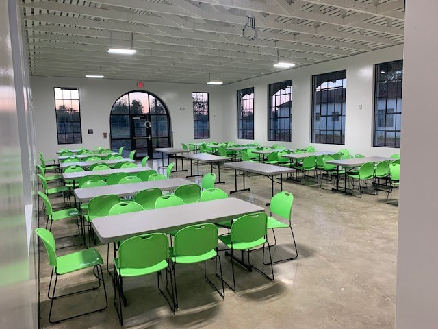 Dining hall with green chairs and long tables