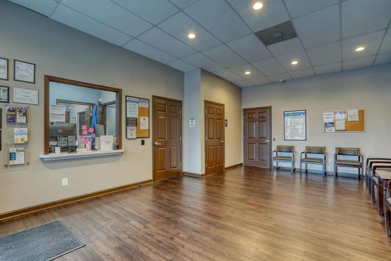 Spacious check-in lobby with reception window, seating, and wood flooring