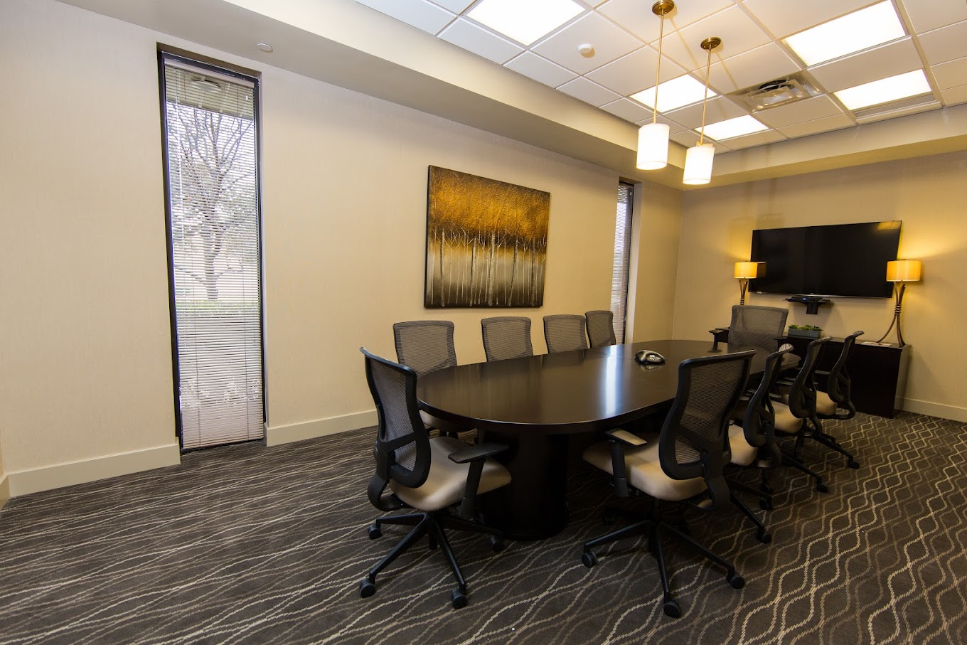Conference room with a large black table, chairs, and a mounted TV