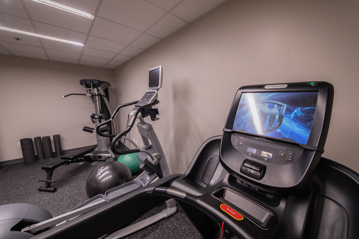 Small gym with treadmill, elliptical, weights, and exercise balls