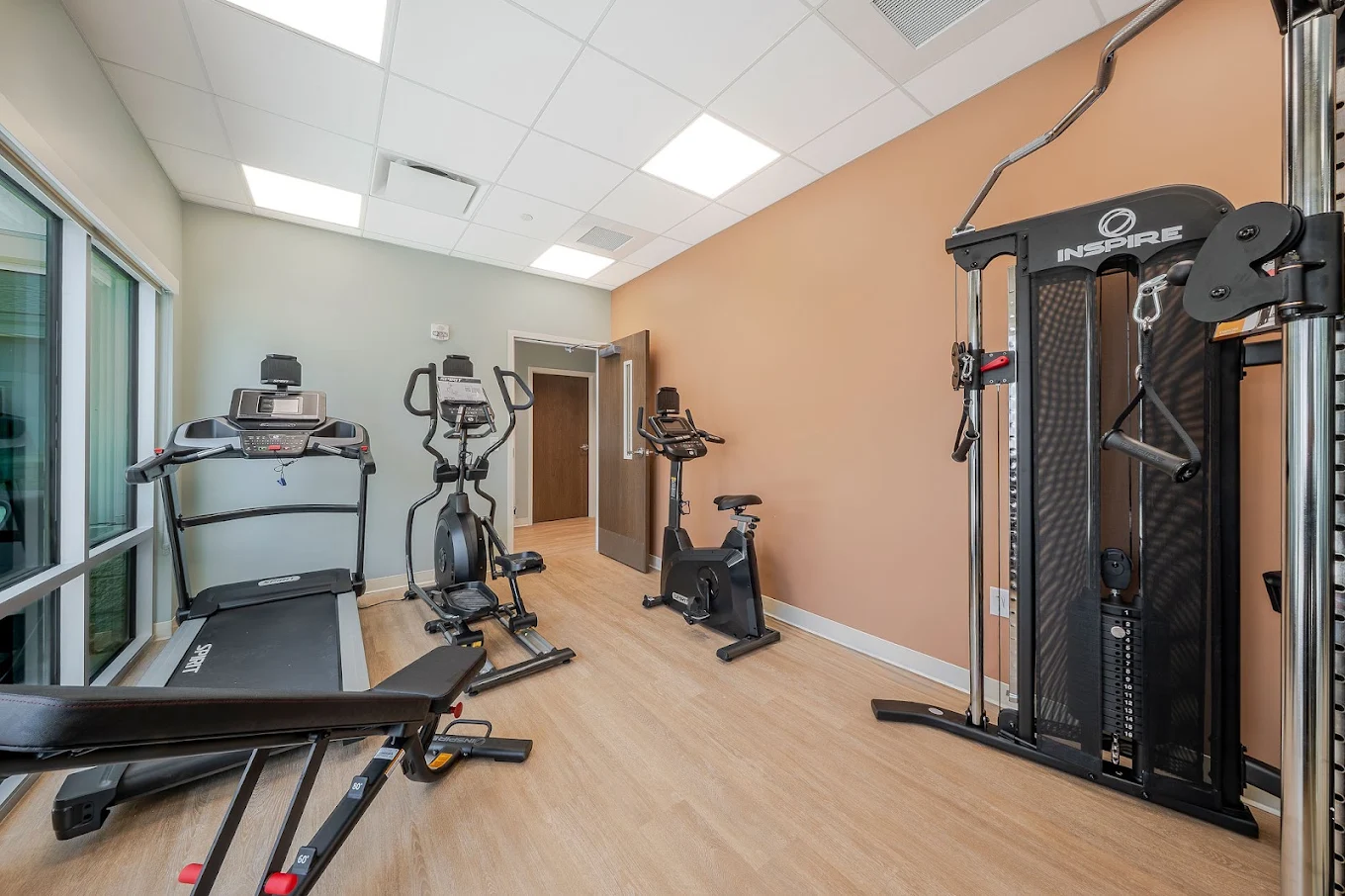 Fitness room with treadmill, elliptical, exercise bike, weight bench, and strength-training equipment